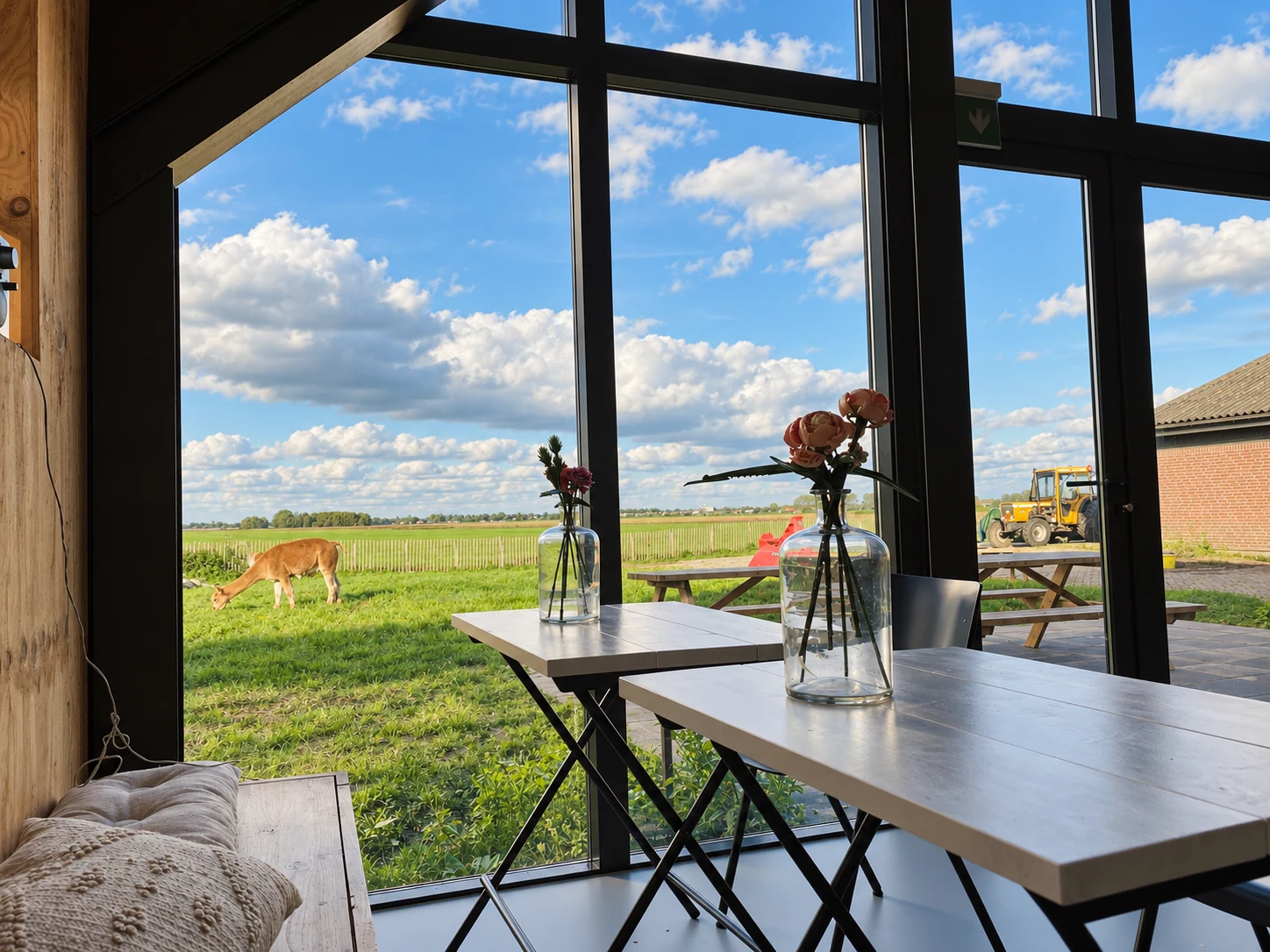 Eettafel bij de glazen gevel met zicht op het terras en een grazende alpaca