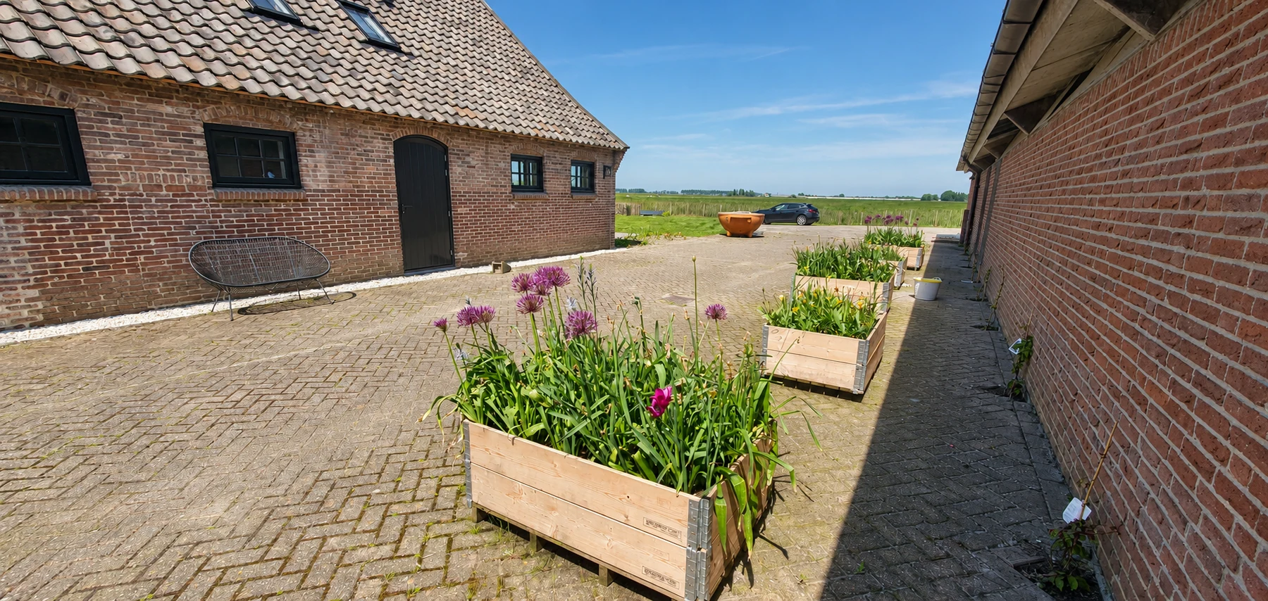 Bloembakken op het erf tussen de historische boerderij en het vakantiehuis